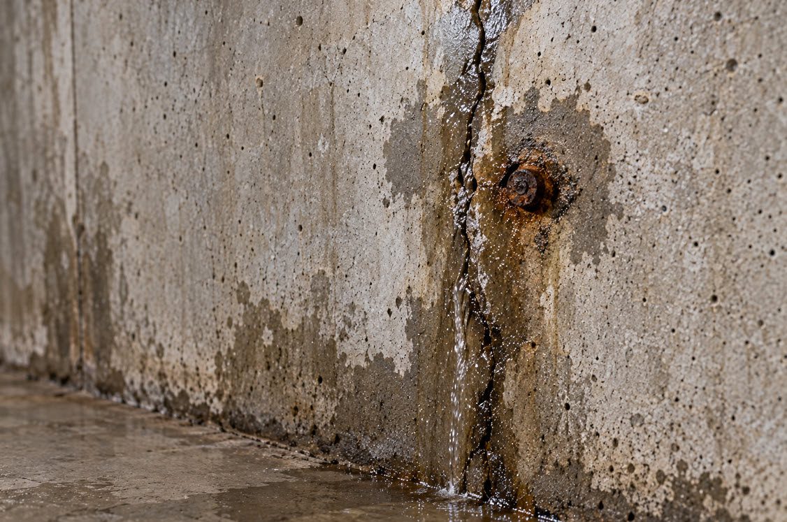 Leaking crack and rusty tie-rod in a poured concrete basement wall